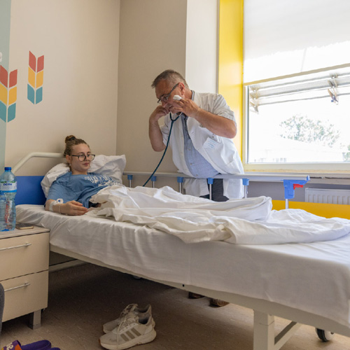 A patient in a hospital bed being treated by a doctor