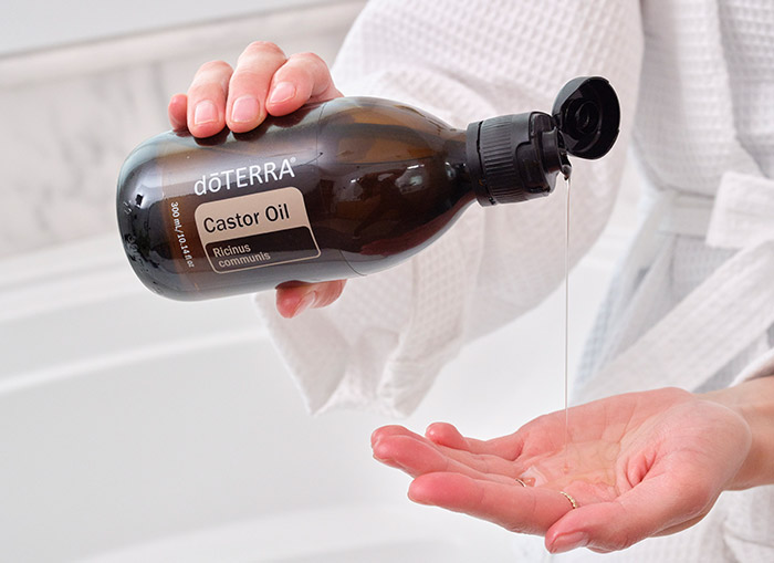 A woman pouring castor oil into her hand