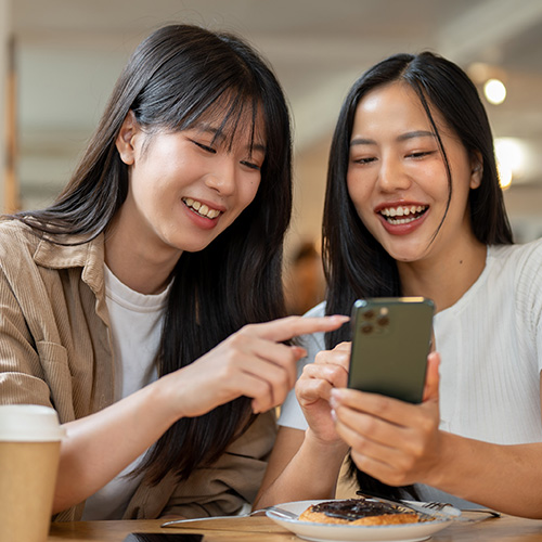 Two women laughing looking at a cell phone