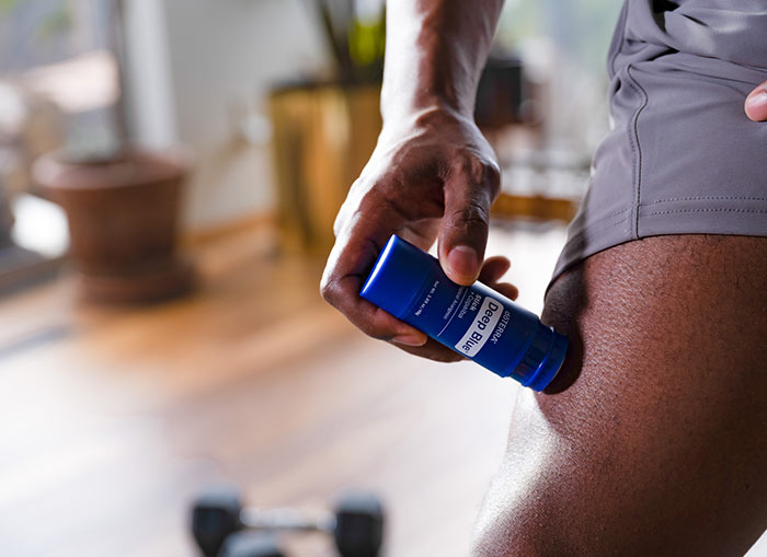 Person applying doTERRA Deep Blue Stick with Copaiba to a sore leg muscle for targeted, soothing relief.