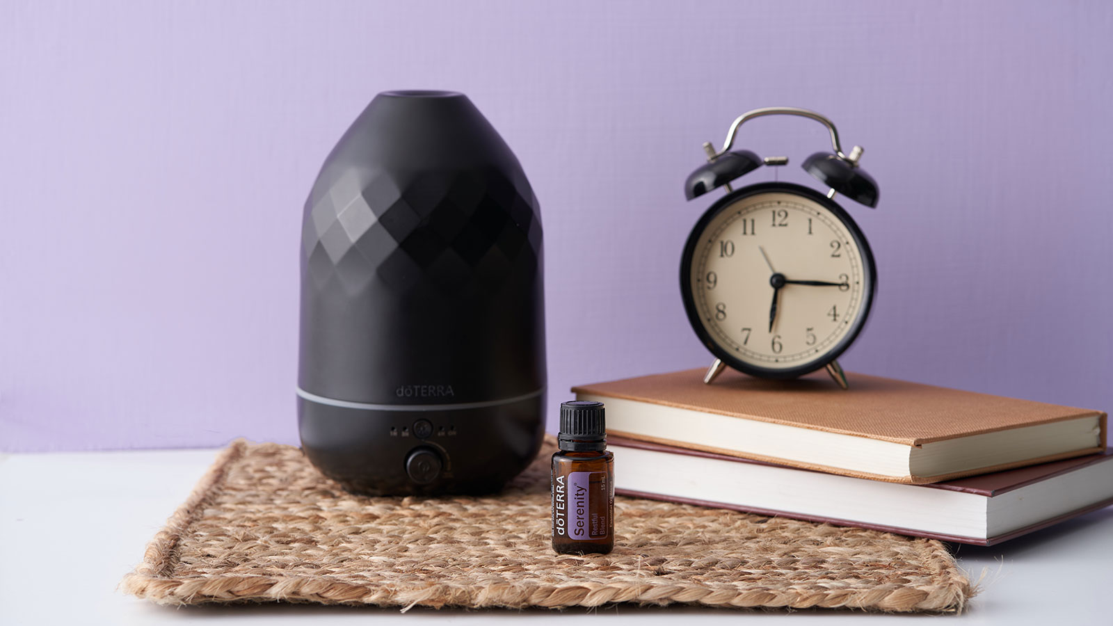 doTERRA Serenity essential oil bottle placed beside a Volo diffuser and an alarm clock, creating a calm, peaceful setting that promotes rest and better sleep.