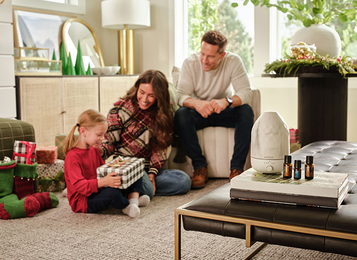 Family unwrapping presents on Christmas with doterra diffuser in foreground