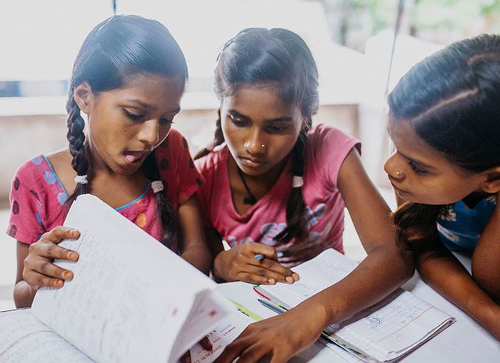 Young girl students at the Bihar campus stand together smiling, wearing school uniforms, made possible through donations from doTERRA Healing Hands.
