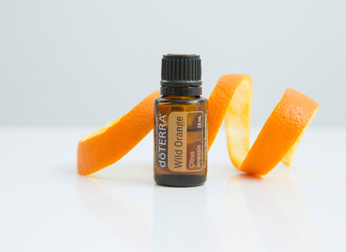 Wild Orange essential oil with an orange peel behind it
