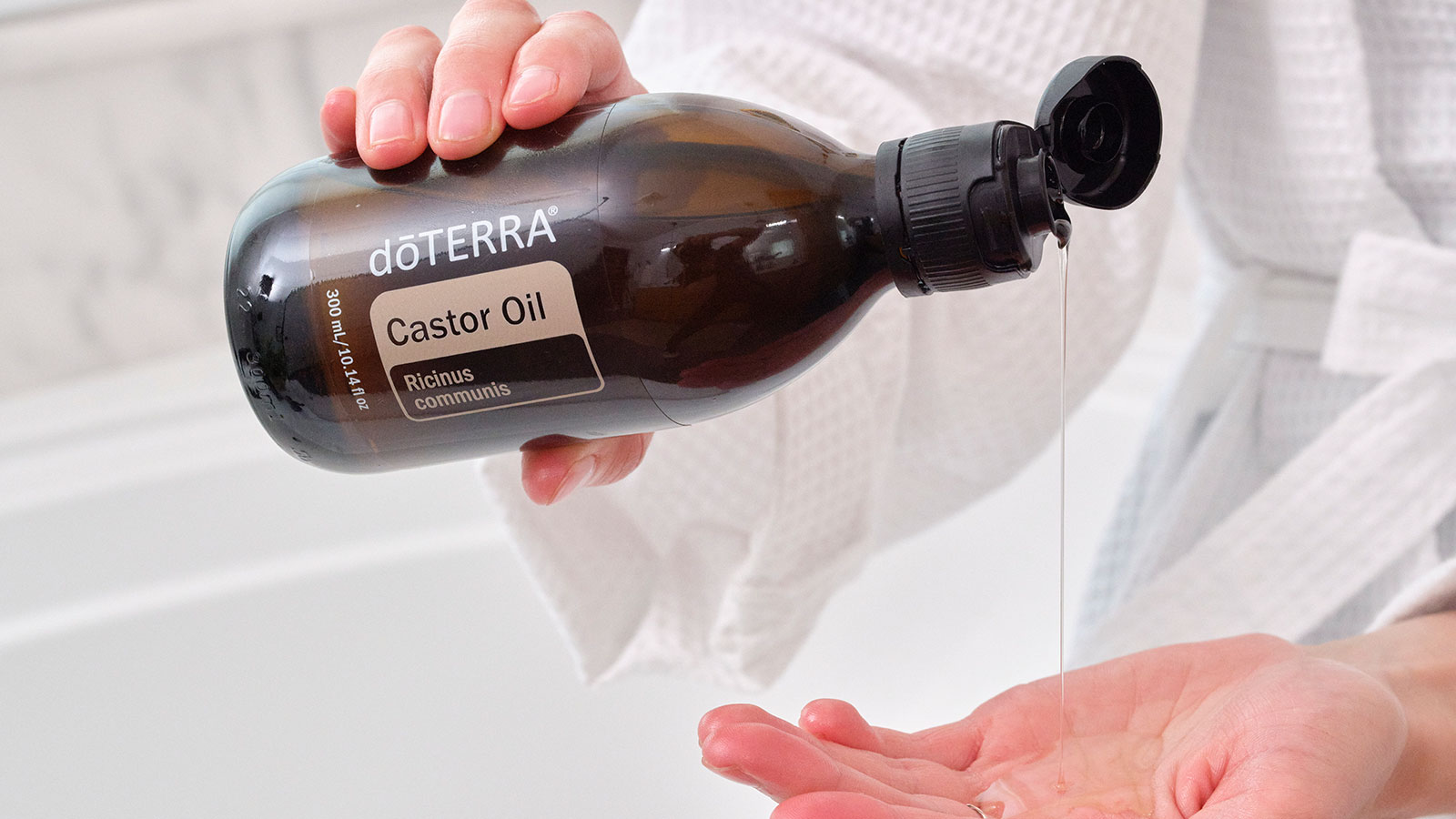 A woman pouring castor oil into her hand