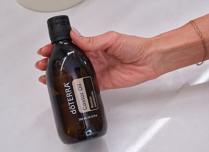 A woman holding a bottle of castor oil