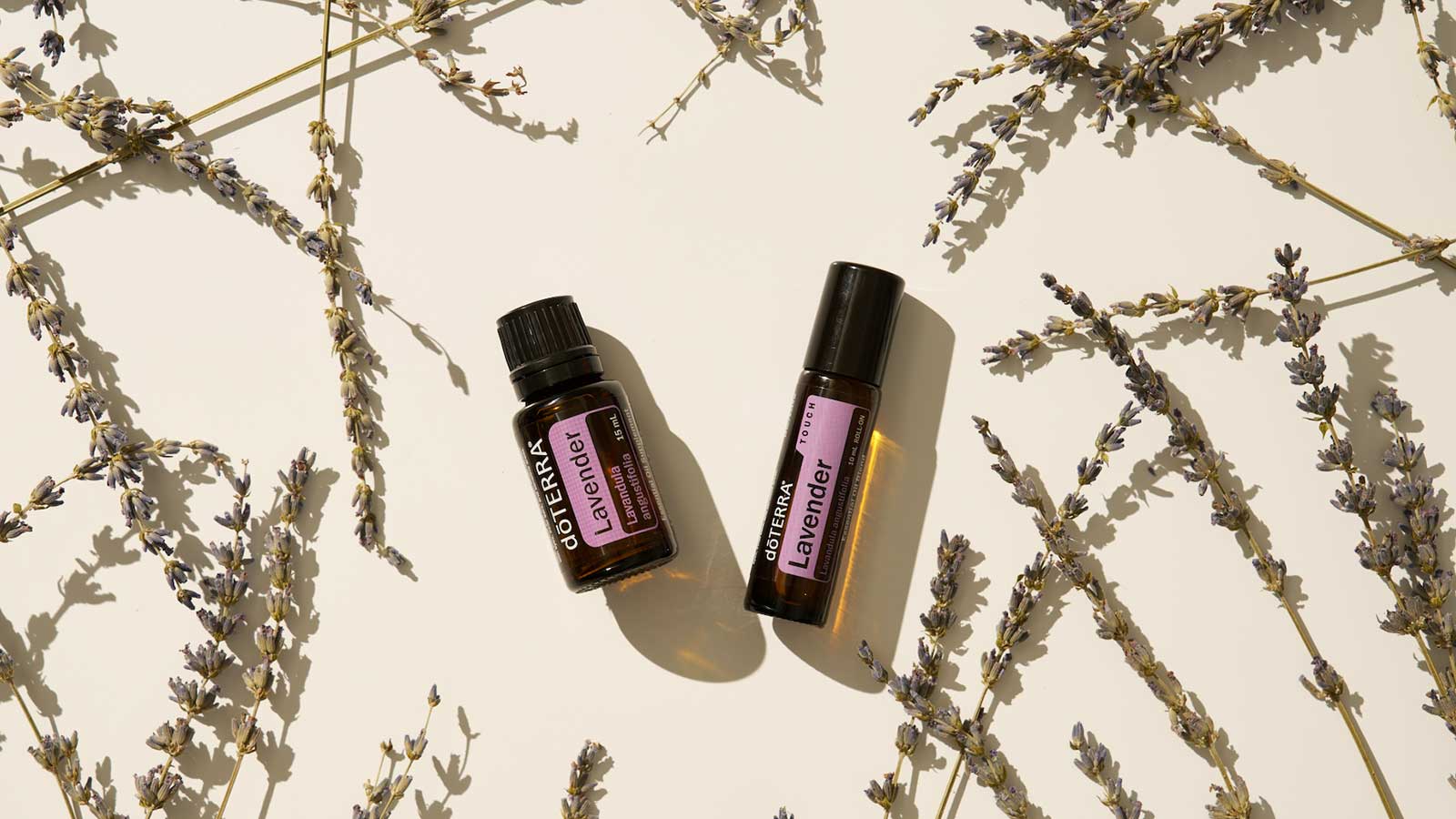 Two bottles of doTERRA essential oil surrounded by lavender plants