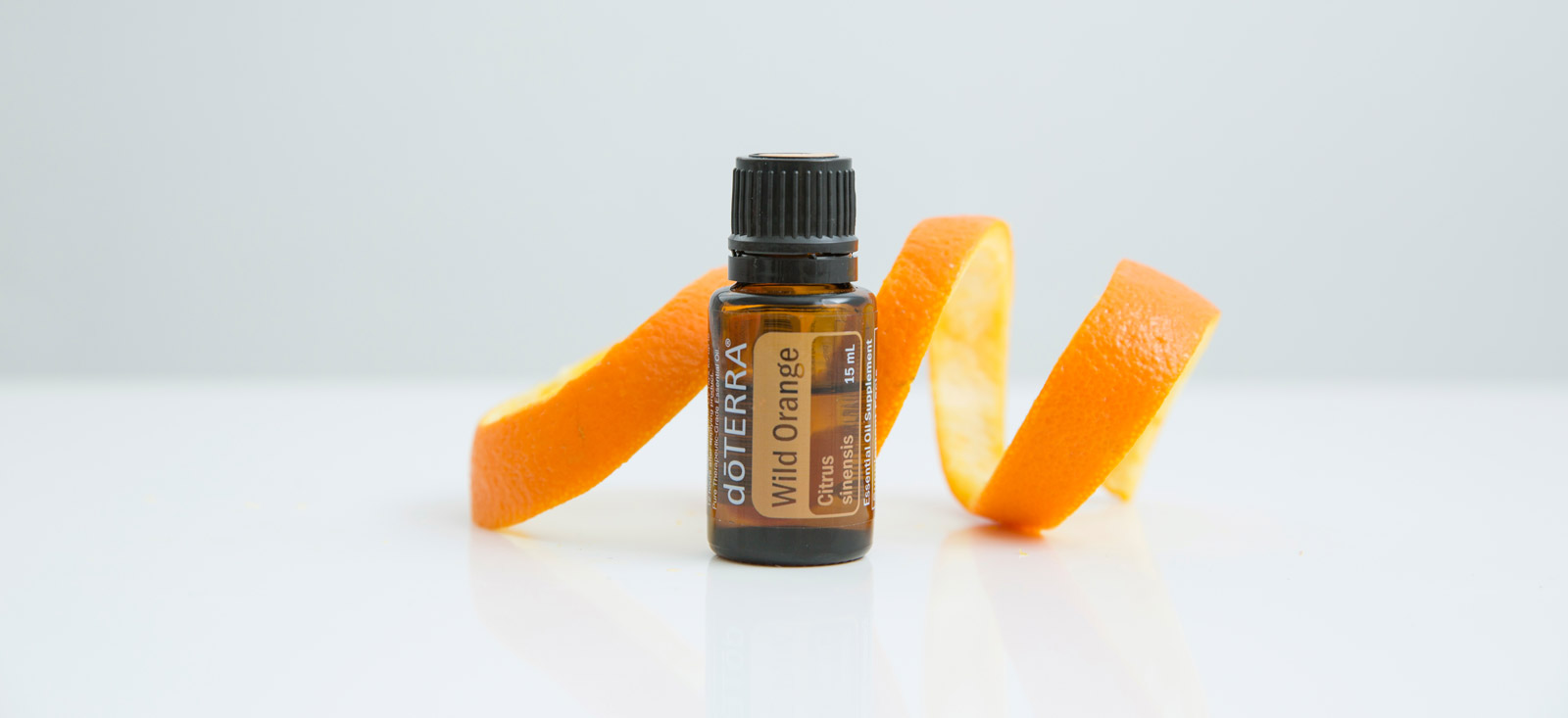 Wild Orange essential oil with an orange peel behind it