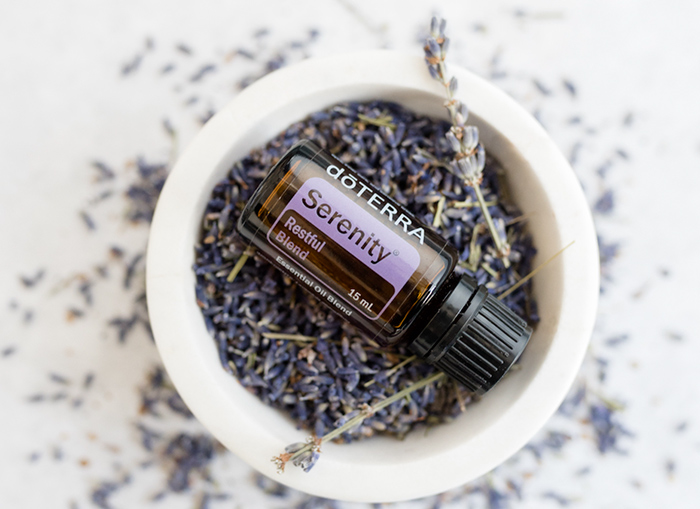 A bottle of doTERRA Serenity Restful Complex oil resting in a bowl filled with fresh sprigs of lavender, creating a calming and soothing visual that highlights the product’s relaxing qualities.